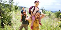 Front view of family with small children hiking outdoors in summer nature.